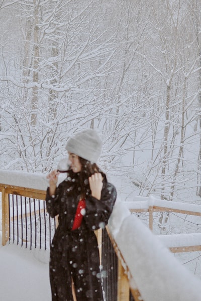 女人黑色上衣和白色针织帽站在冰雪覆盖的地面白天
